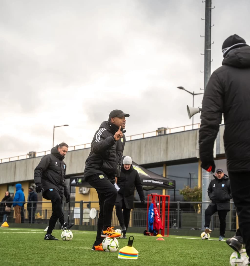 Trainer begeleidt een voetbaltechnische veldsessie